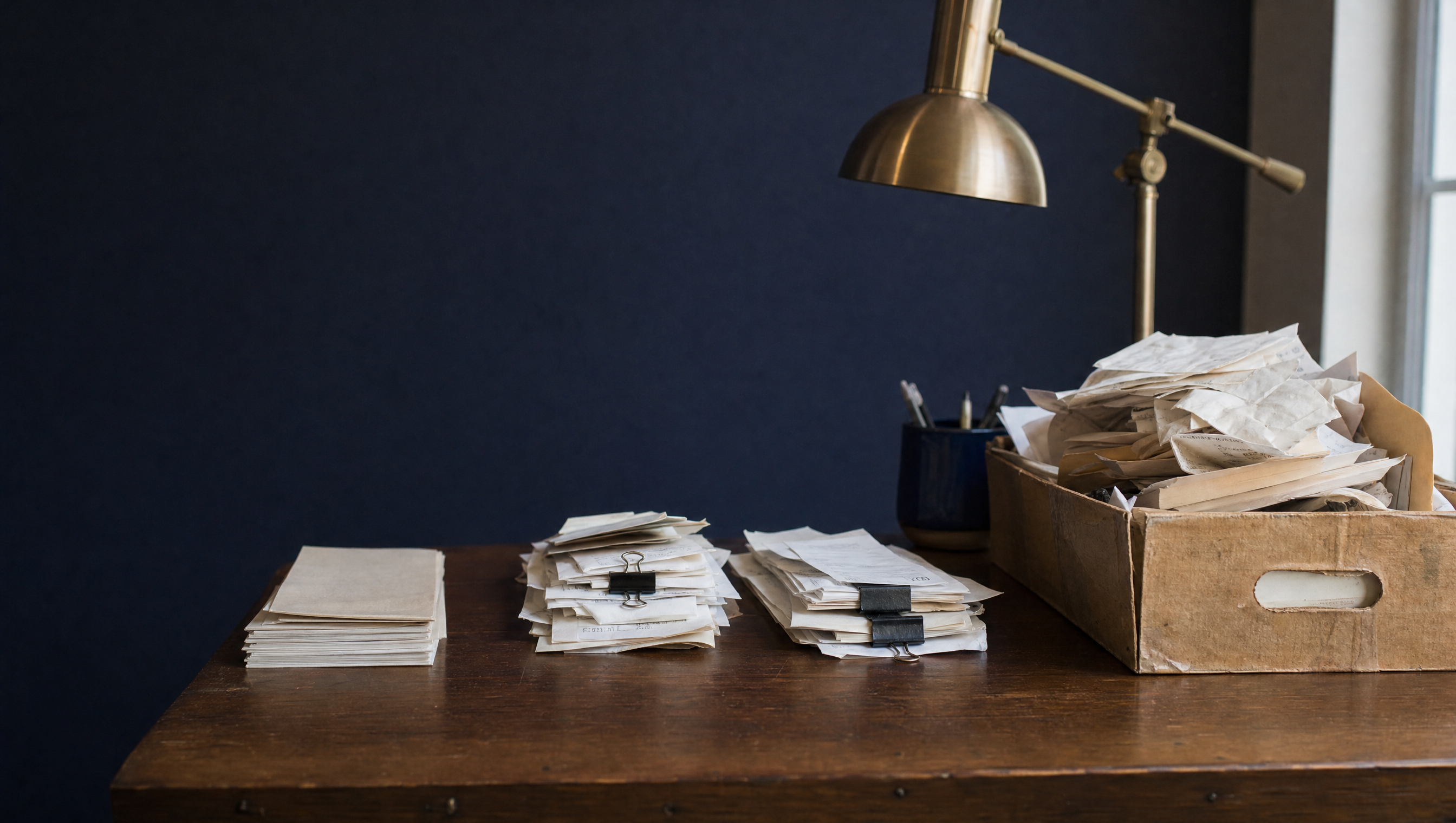 Receipts sorted into clipped stacks on a desk, next to a box of unsorted papers.